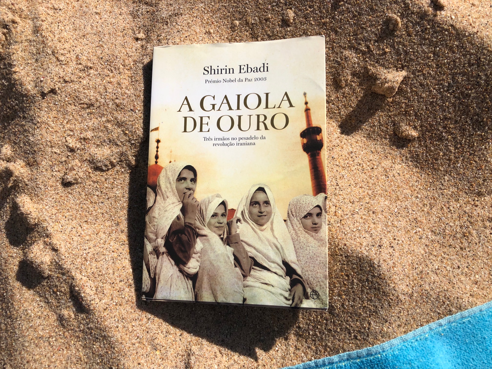 Foto do livro «A gaiola de ouro» na areia da praia